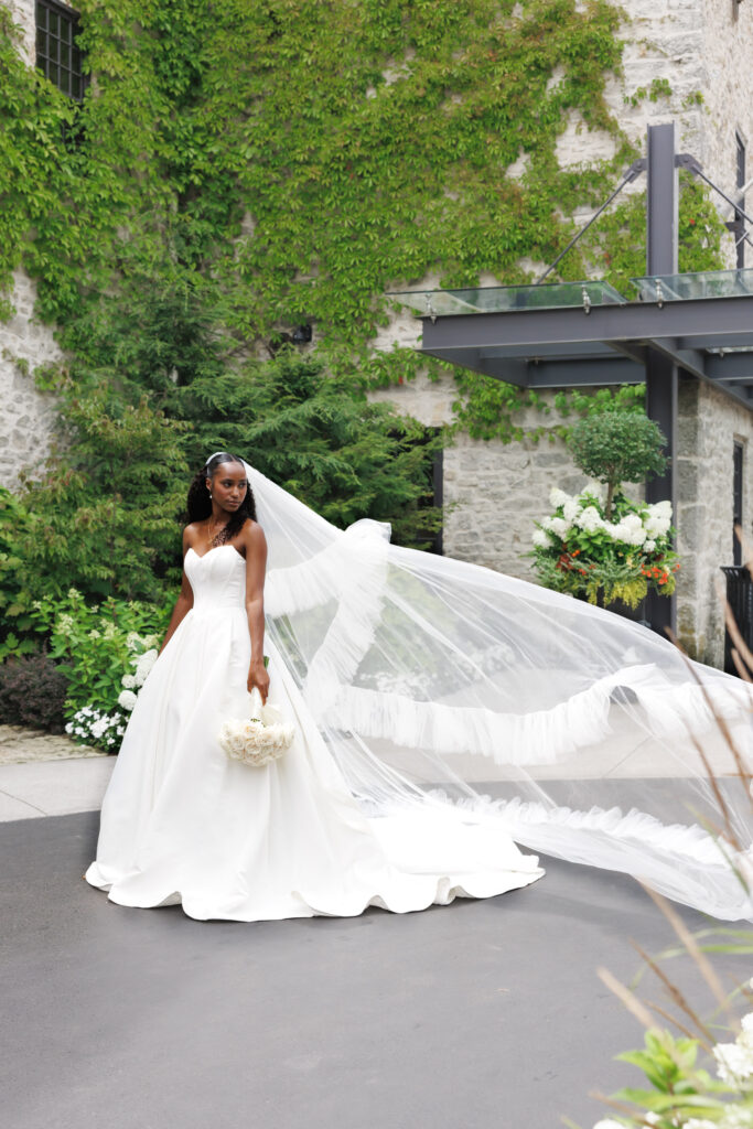 Bride with flowing veil outside Elora Mill wedding venue in Cambridge, Ontario.