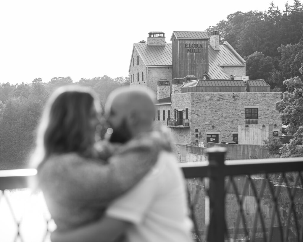 Couple kissing outside Elora Mill during Ontario engagement photos.