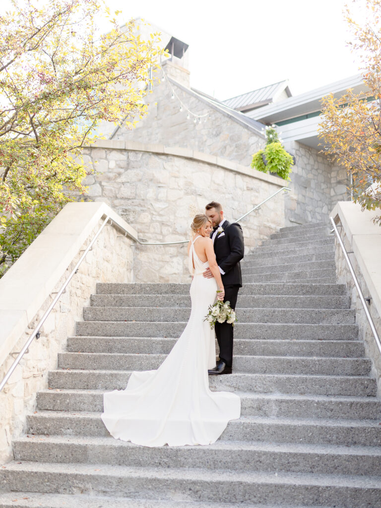Bride and groom embracing on the stone staircase at Cambridge Mill, captured by Furtado Photo Co., Cambridge wedding photographer.