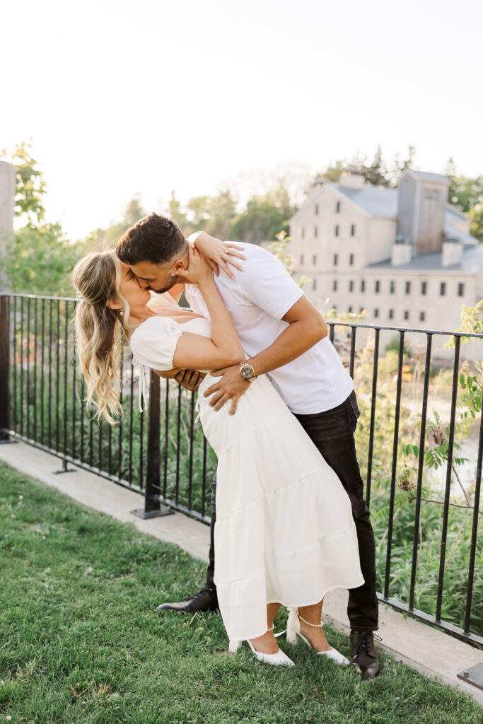 Couple kissing during golden hour at Elora Mill, romantic dip pose with historic stone mill in the background