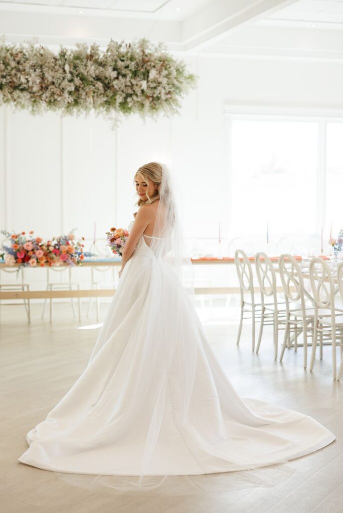 bride with back of dress showing in the reception space at elle by stella wedding 