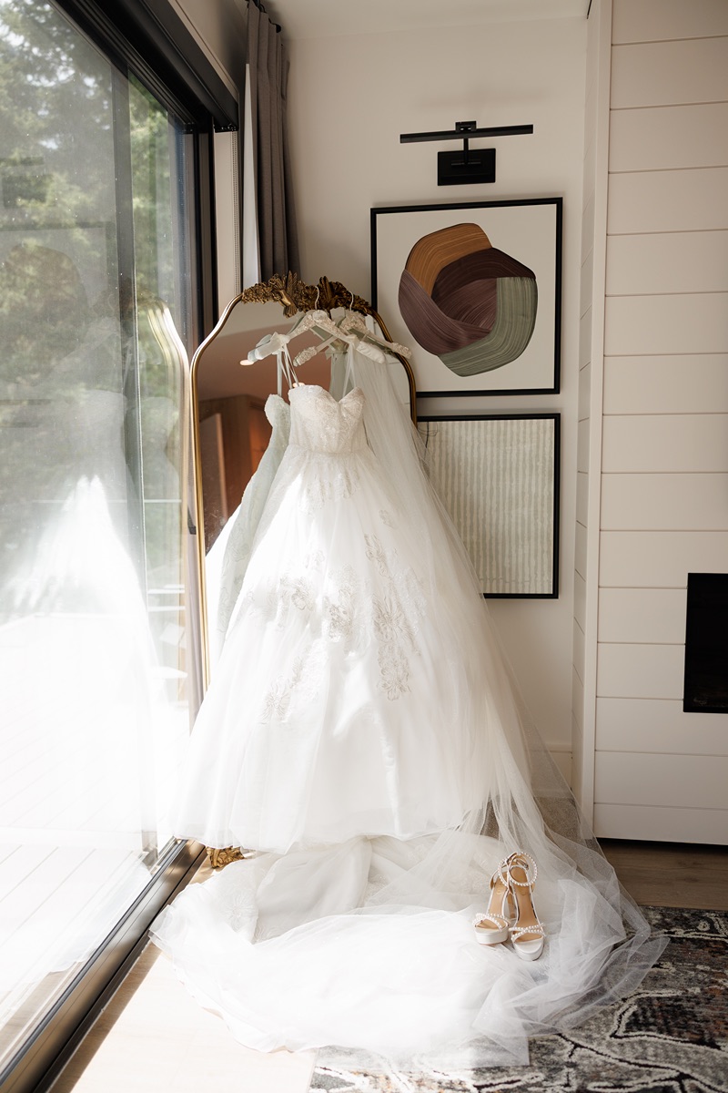 Bride lace gown hanging by modern glass window at TPC Osprey Valley wedding in Caledon